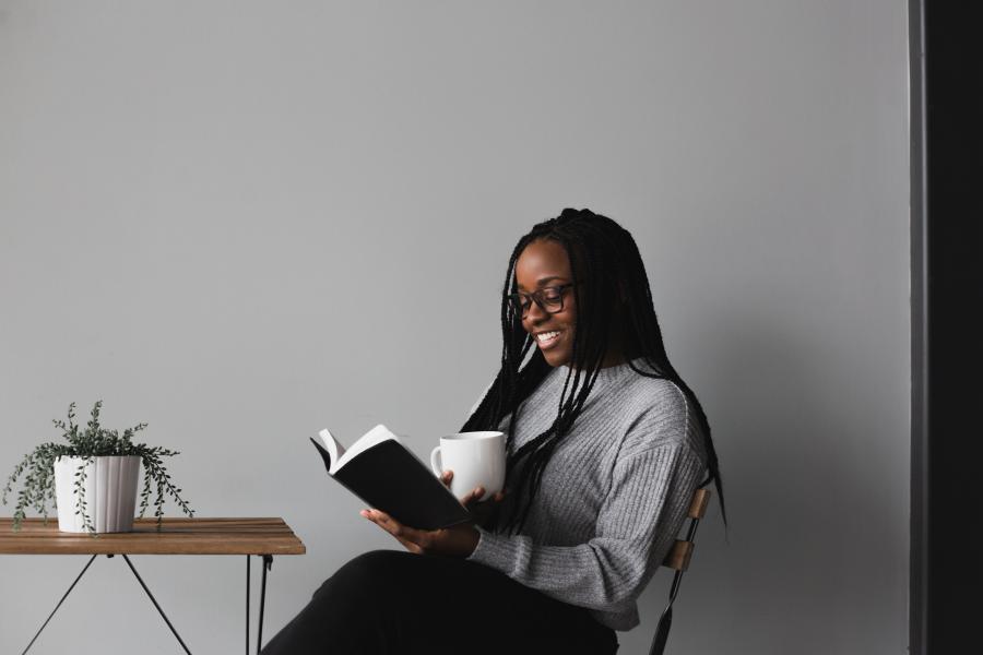 En kvinde sidder ved et bord med en kop og en åben bog