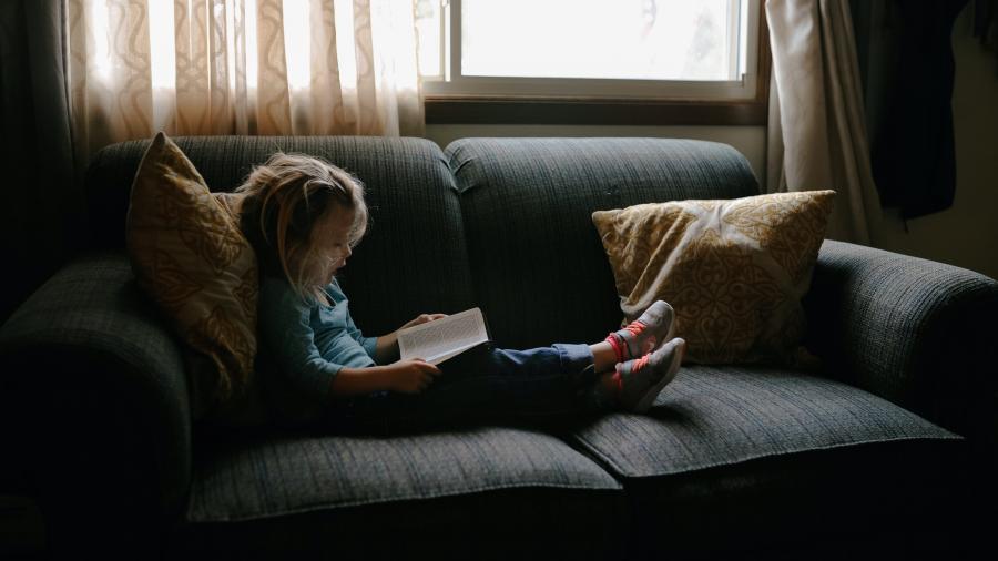 lille pige der læser i sofa