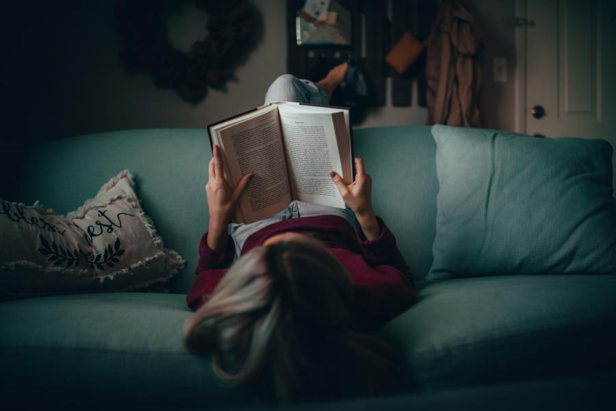Kvinde der læser i sofaen, set ovenfra