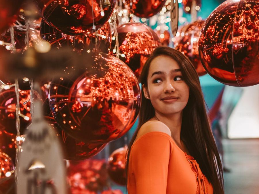 Ung pige omgivet af store røde juledekorationer
